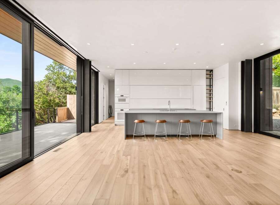 Experience modern living in this stunning open-concept kitchen and living area, featuring sleek white cabinetry and a large island with bar seating.
