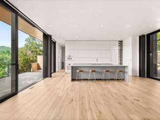 Experience modern living in this stunning open-concept kitchen and living area, featuring sleek white cabinetry and a large island with bar seating.