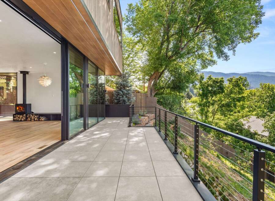 Experience seamless indoor-outdoor living with this stunning modern home, featuring expansive glass doors that open onto a spacious tiled patio.