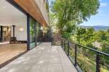 Experience seamless indoor-outdoor living with this stunning modern home, featuring expansive glass doors that open onto a spacious tiled patio.
