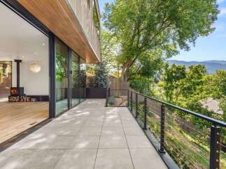 Experience seamless indoor-outdoor living with this stunning modern home, featuring expansive glass doors that open onto a spacious tiled patio.