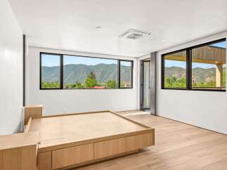 Experience breathtaking mountain views from this modern bedroom, featuring expansive windows that frame the stunning landscape.