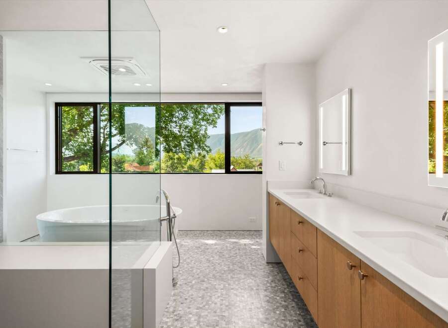 Experience luxury in this modern bathroom featuring a freestanding soaking tub with a stunning mountain view.