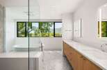 Experience luxury in this modern bathroom featuring a freestanding soaking tub with a stunning mountain view.