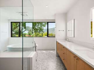 Experience luxury in this modern bathroom featuring a freestanding soaking tub with a stunning mountain view.