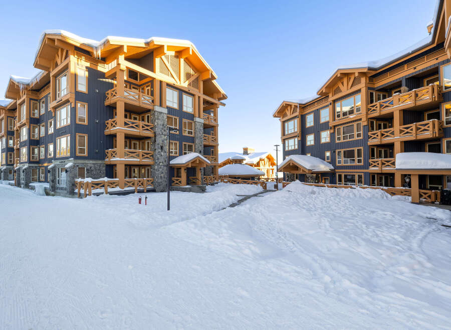 Experience luxury mountain living in this stunning ski resort property, featuring a modern architectural design with warm wood accents and dark blue siding.