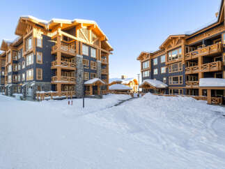 Experience luxury mountain living in this stunning ski resort property, featuring a modern architectural design with warm wood accents and dark blue siding.