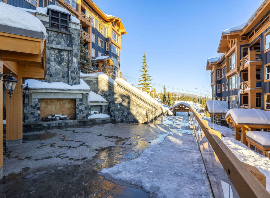 Experience luxury mountain living in this stunning property, featuring a grand stone fireplace and elegant wooden architecture.