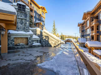 Experience luxury mountain living in this stunning property, featuring a grand stone fireplace and elegant wooden architecture.