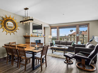 Experience luxury living in this stunning dining and living area, featuring a unique live-edge dining table and a cozy fireplace.