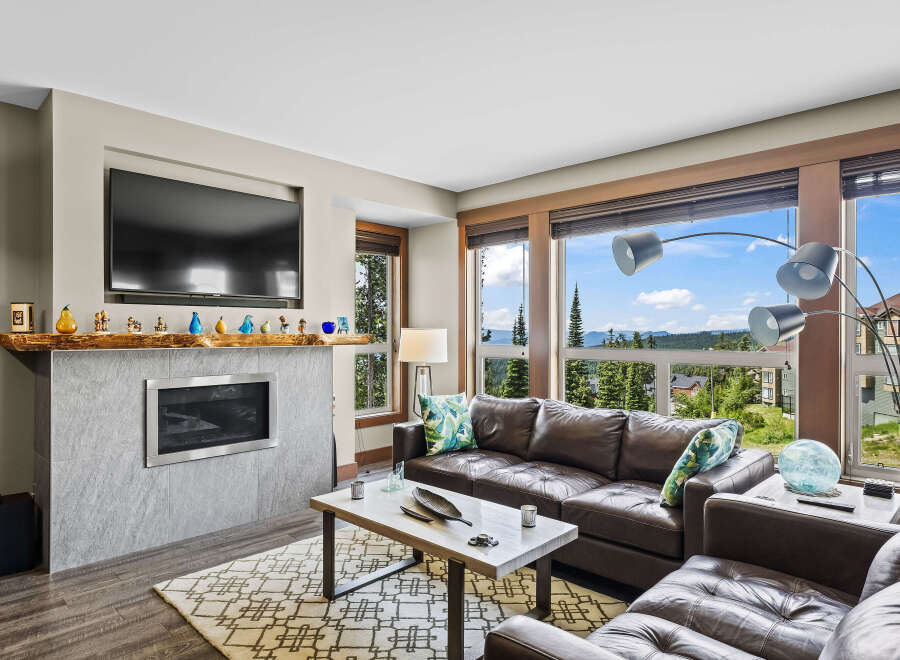 Experience breathtaking mountain views from this stunning living room, featuring a modern fireplace and a luxurious leather sectional.