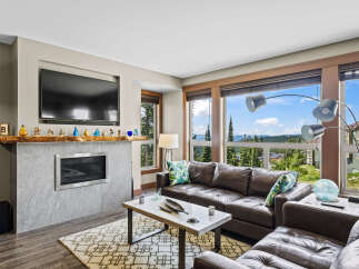 Experience breathtaking mountain views from this stunning living room, featuring a modern fireplace and a luxurious leather sectional.