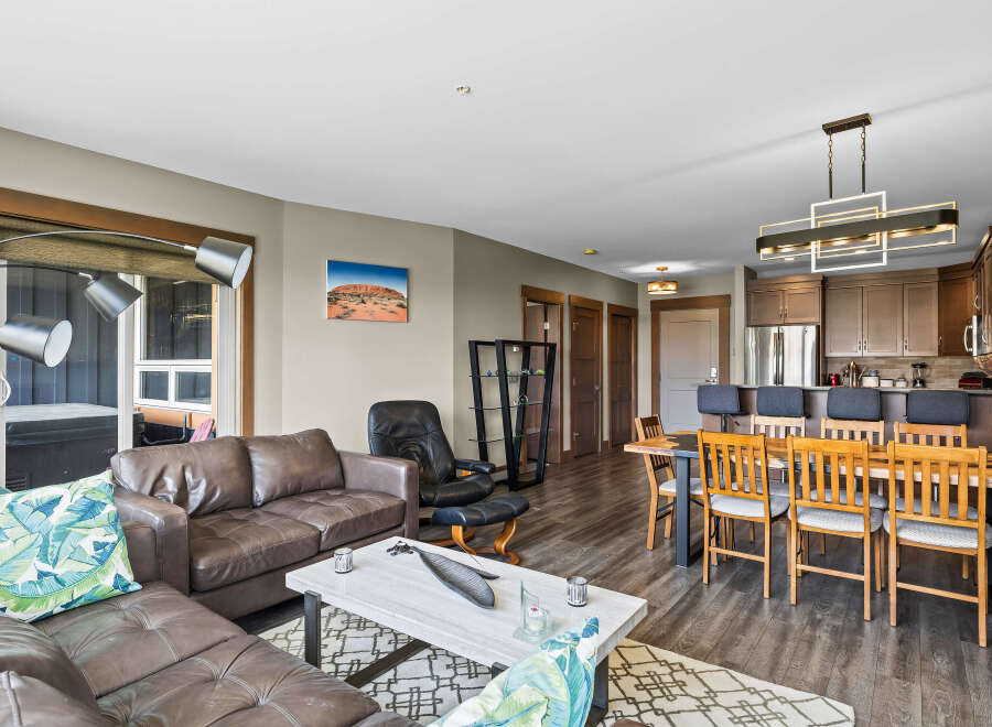 Experience modern living in this spacious open-concept condo, featuring a comfortable leather sectional sofa and a stylish dining area perfect for entertaining.