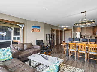Experience modern living in this spacious open-concept condo, featuring a comfortable leather sectional sofa and a stylish dining area perfect for entertaining.