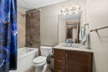 This modern bathroom features a sleek white bathtub with a stylish shower head and a unique blue abstract shower curtain.