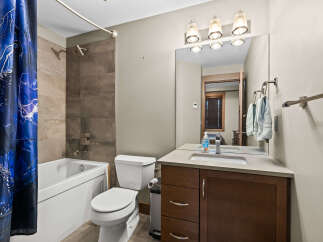 This modern bathroom features a sleek white bathtub with a stylish shower head and a unique blue abstract shower curtain.