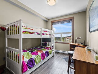 This charming bedroom features a white bunk bed with vibrant, colorful bedding, perfect for accommodating guests or children.