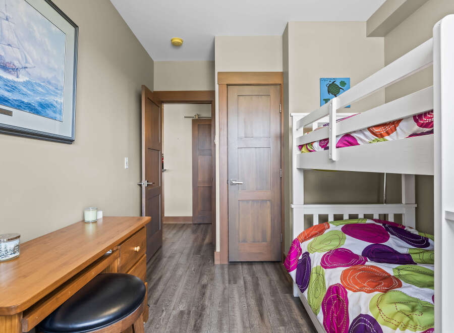 This charming bedroom features a white bunk bed with colorful bedding, perfect for accommodating guests or children.