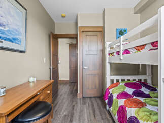 This charming bedroom features a white bunk bed with colorful bedding, perfect for accommodating guests or children.