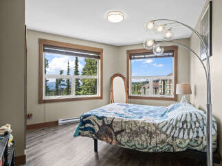 Experience breathtaking mountain views from this charming bedroom, featuring a comfortable bed adorned with a unique duvet cover.