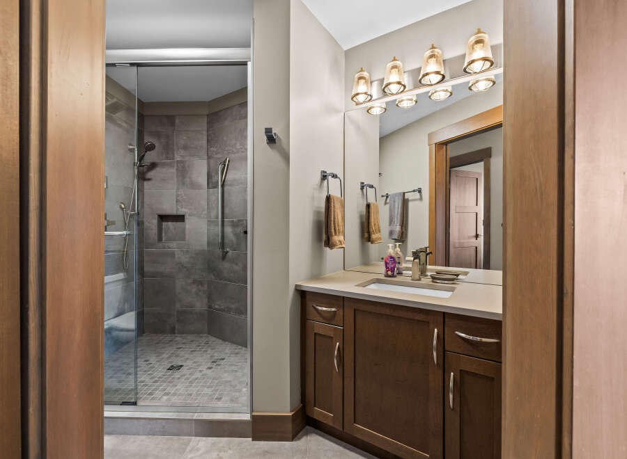 Experience luxury in this modern bathroom, featuring a spacious glass-enclosed shower with elegant tilework and a sleek vanity with ample storage.