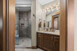 Experience luxury in this modern bathroom, featuring a spacious glass-enclosed shower with elegant tilework and a sleek vanity with ample storage.