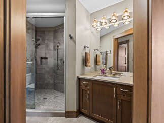 Experience luxury in this modern bathroom, featuring a spacious glass-enclosed shower with elegant tilework and a sleek vanity with ample storage.