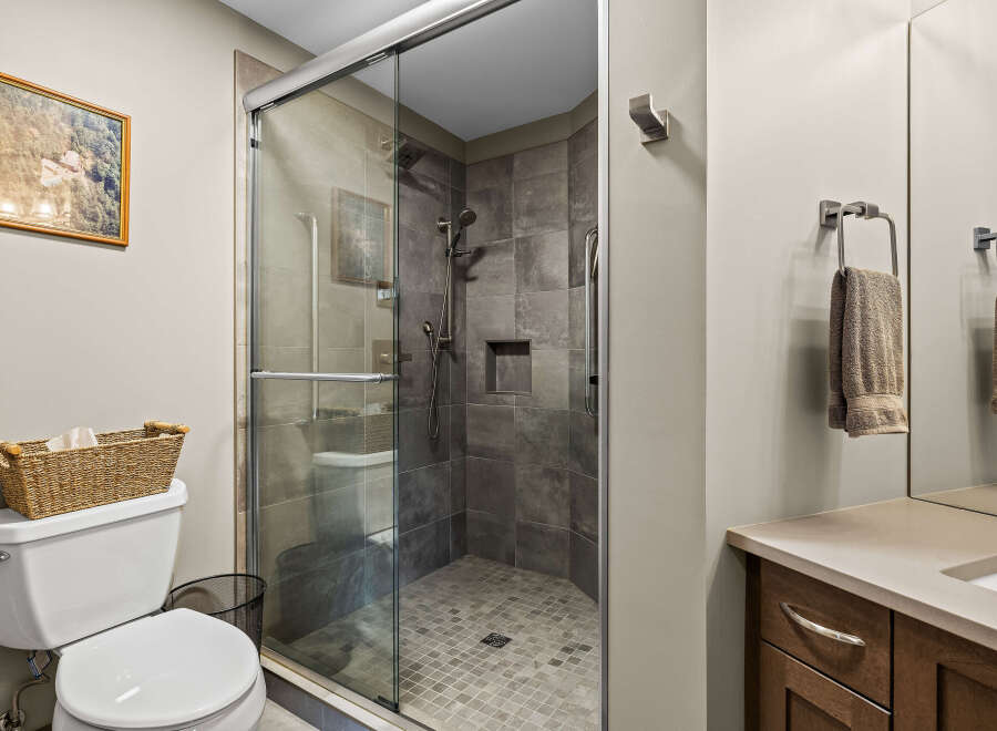 Experience modern comfort in this beautifully appointed bathroom, featuring a spacious glass-enclosed shower with sleek tilework and a convenient built-in niche.