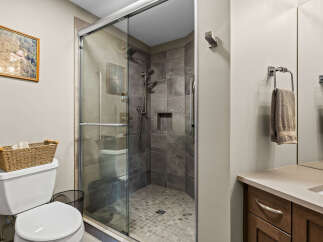 Experience modern comfort in this beautifully appointed bathroom, featuring a spacious glass-enclosed shower with sleek tilework and a convenient built-in niche.