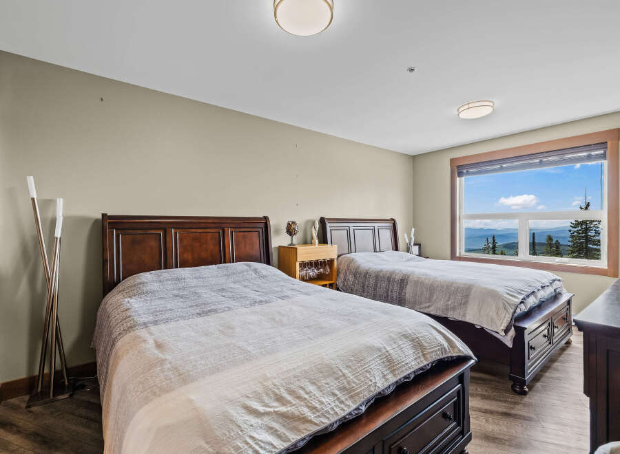 Experience breathtaking mountain views from this spacious bedroom, featuring two comfortable queen-sized beds perfect for families or groups.