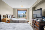 Experience breathtaking mountain views from this stunning bedroom, featuring two comfortable beds and a large window overlooking a serene landscape.