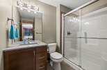 This modern bathroom features a sleek vanity with ample storage and a clean white sink, complemented by a large mirror and stylish light fixtures.