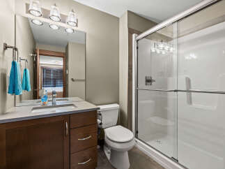 This modern bathroom features a sleek vanity with ample storage and a clean white sink, complemented by a large mirror and stylish light fixtures.