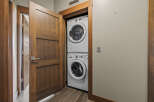 Discover the convenience of in-suite laundry with this stacked GE washer and dryer set, neatly tucked away behind a stylish wooden door.