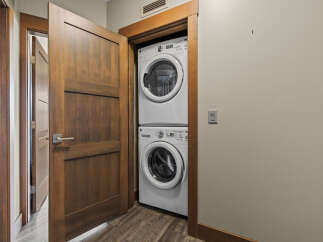 Discover the convenience of in-suite laundry with this stacked GE washer and dryer set, neatly tucked away behind a stylish wooden door.