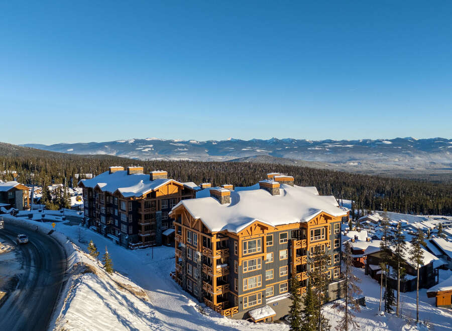 Experience luxury mountain living in this stunning ski resort property, featuring modern architecture with rustic wood accents and ample snow-covered balconies.