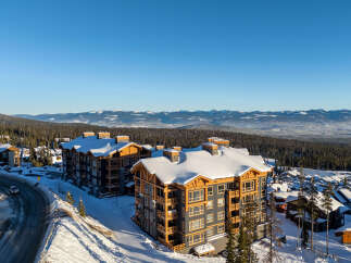 Experience luxury mountain living in this stunning ski resort property, featuring modern architecture with rustic wood accents and ample snow-covered balconies.