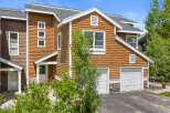 Charming townhome featuring warm wood siding and a welcoming entrance.
