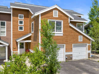 Charming townhome featuring warm wood siding and a welcoming entrance.