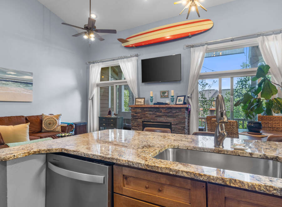 Experience coastal living in this beautifully appointed home, featuring a spacious kitchen island with granite countertops and a deep stainless steel sink.