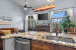 Experience coastal living in this beautifully appointed home, featuring a spacious kitchen island with granite countertops and a deep stainless steel sink.