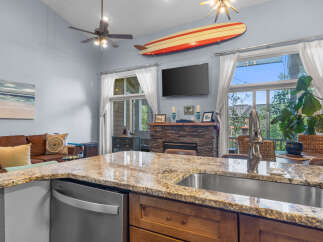 Experience coastal living in this beautifully appointed home, featuring a spacious kitchen island with granite countertops and a deep stainless steel sink.