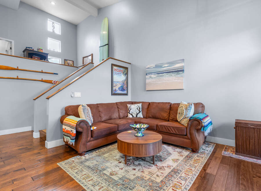 This inviting living room features a spacious brown leather sectional sofa adorned with colorful throw pillows and blankets, perfect for cozy gatherings.