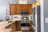 This kitchen boasts beautiful natural wood cabinetry, complemented by a sleek stainless steel appliance suite including a microwave, gas range, and refrigerator.