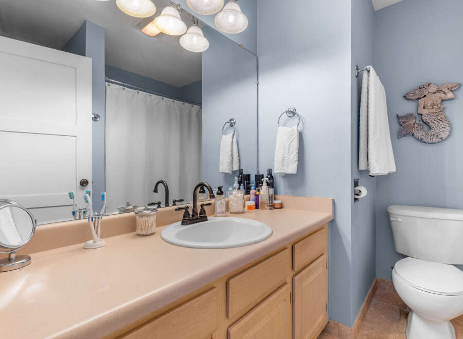 This charming bathroom features a light beige vanity with ample counter space, complemented by a white undermount sink and a dark bronze faucet.