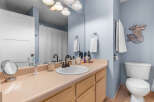 This charming bathroom features a light beige vanity with ample counter space, complemented by a white undermount sink and a dark bronze faucet.