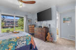 This inviting bedroom features a comfortable bed with a vibrant, patchwork quilt and a large sliding glass door offering scenic views of the outdoors.