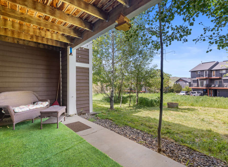 Enjoy outdoor living on this charming patio, complete with a wicker loveseat and coffee table, perfect for relaxing.