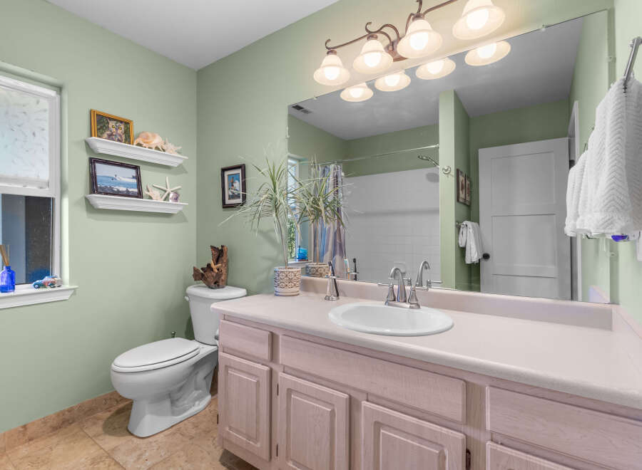 This charming bathroom features a light green accent wall, complemented by a spacious vanity with ample storage.