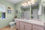 This charming bathroom features a light green accent wall, complemented by a spacious vanity with ample storage.